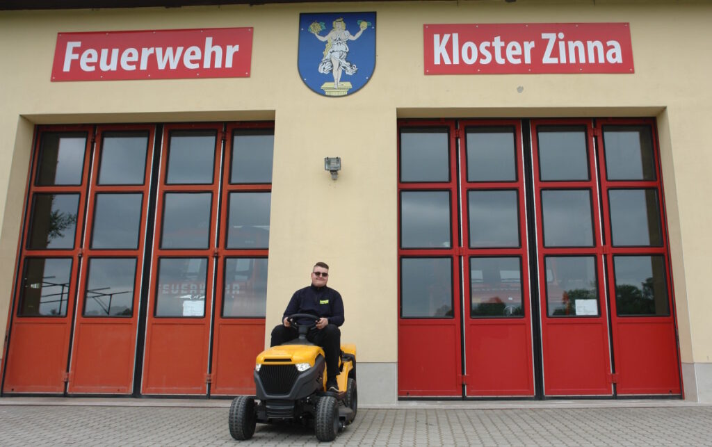 Erik Jonscher auf dem Rasenmäher vor dem Gerätehaus der Freiwilligen Feuerwehr Kloster Zinna.