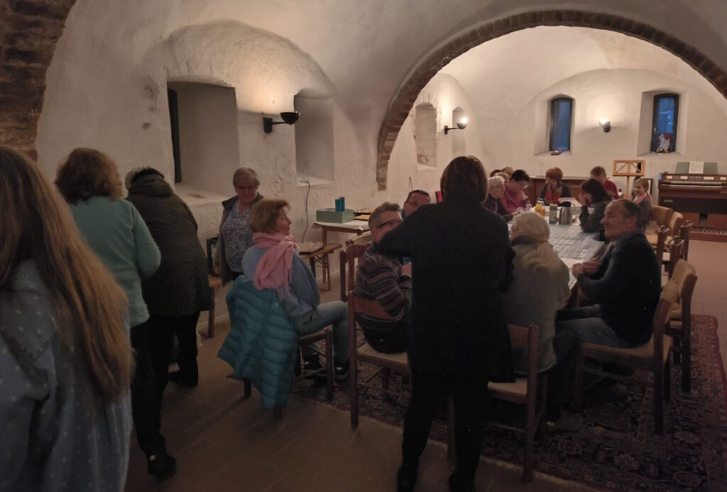 Blick durch das Konversenhaus mit den Besuchern am und um den langen Tisch.