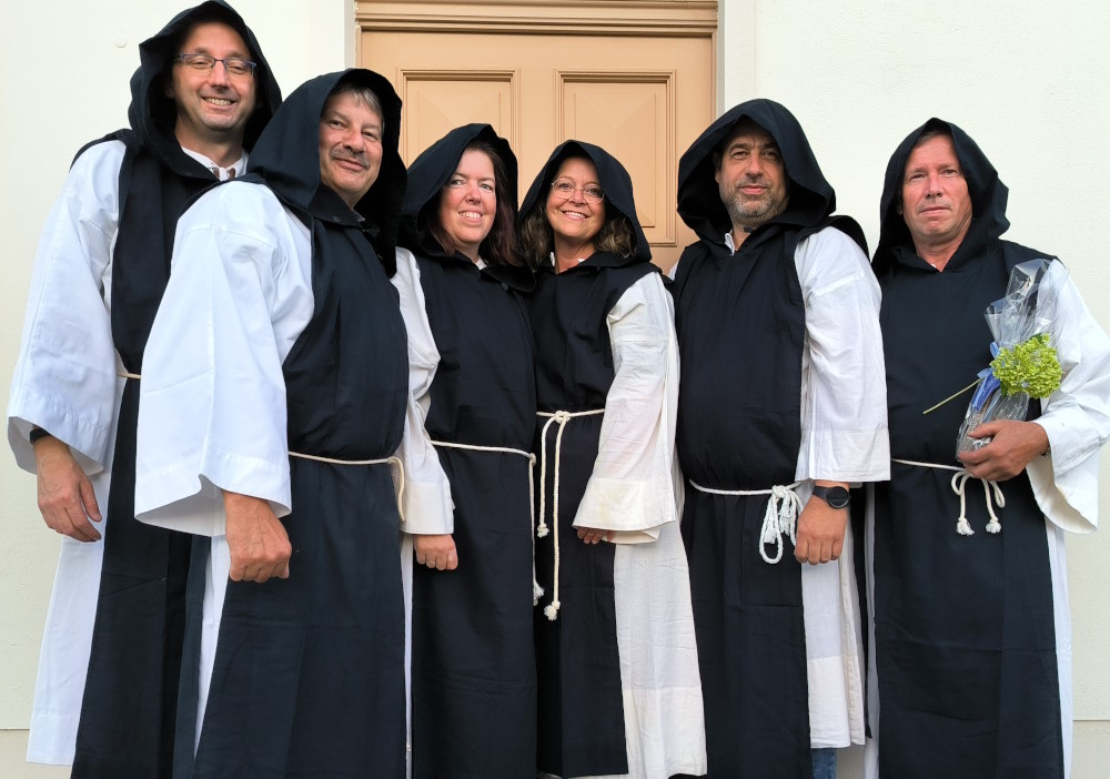 Sechs Mönche aus Kloster Zinna stehen vor einem historischen Gebäude.